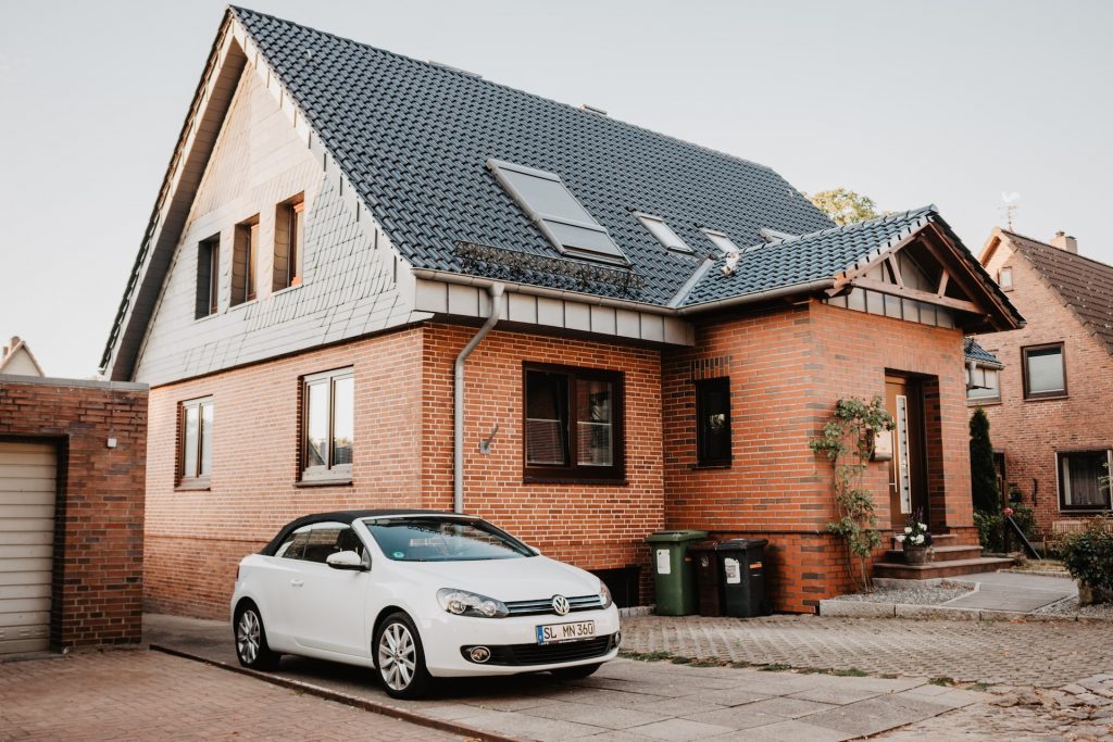 car near the house with metal roof