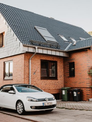car near the house with metal roof